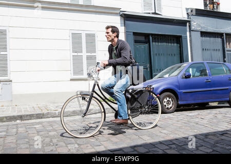 Mitte erwachsenen Mannes Beschleunigung nach unten gepflasterten Stadtstraße auf Fahrrad Stockfoto