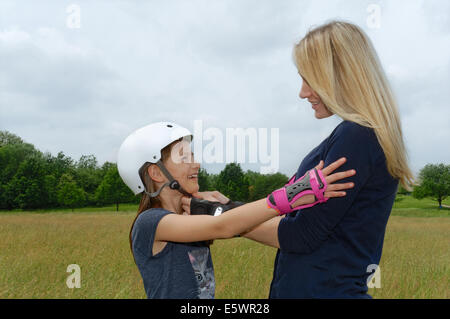 Mutter Befestigung Tochter Rollerblading Helm im park Stockfoto