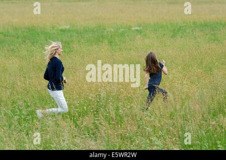 Mutter und Tochter läuft durch lange Wiese Stockfoto