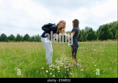 Mutter und Tochter riechen Wildblumen im Feld Stockfoto