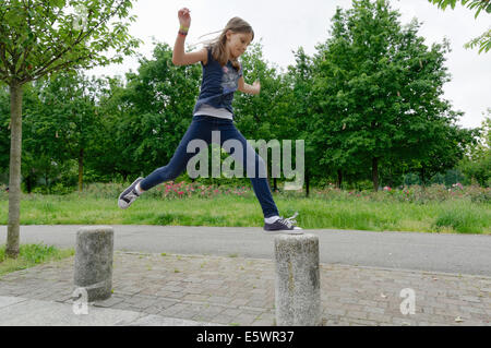 Mädchen springen Poller Mitte Luft im park Stockfoto
