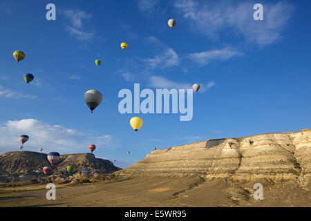 Große Gruppe von Heißluftballons schweben in Ferne über Berge, Kappadokien, Anatolien, Türkei Stockfoto