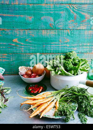 Stillleben mit roher frischer Minze, Süßkartoffeln, Babykarotten, Chilis, Zwiebeln, Knoblauch, Eschallots, grüne Bohnen, Grünkohl und Mangold Stockfoto