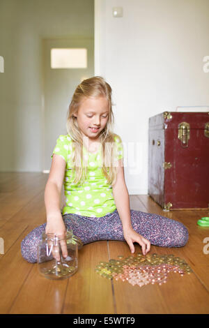 Mädchen zählen Münzen aus Einsparungen Glas Stockfoto