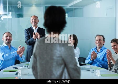Unternehmerinnen und Unternehmern rund um Konferenztisch applaudieren Stockfoto