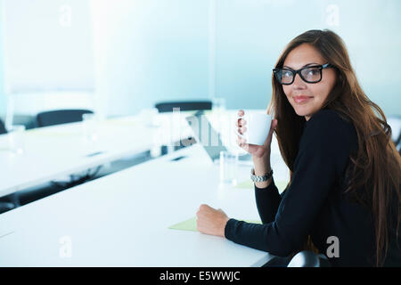 Porträt der Geschäftsfrau Kaffeetrinken am Konferenztisch Stockfoto