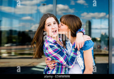 Zwei junge Frauen mit Kuss auf die Wange umarmt herumalbern Stockfoto