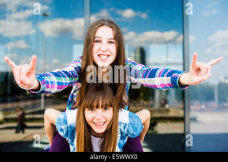 Zwei junge Frauen, Huckepack, so dass ich Sie Liebe Geste der hand Stockfoto
