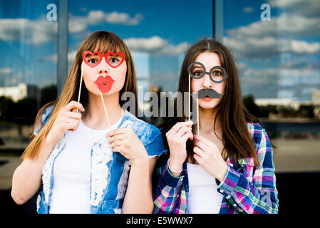 Porträt zweier junger Frauen, Lippen- und Augenpflege Kostüm Masken hochhalten Stockfoto