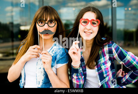 Porträt von zwei jungen Frauen hält Schnurrbart und Brille Kostüm Masken Stockfoto