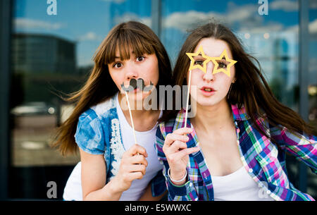 Porträt zweier junger Frauen, Schnurrbart und Brille Kostüm Masken hochhalten Stockfoto