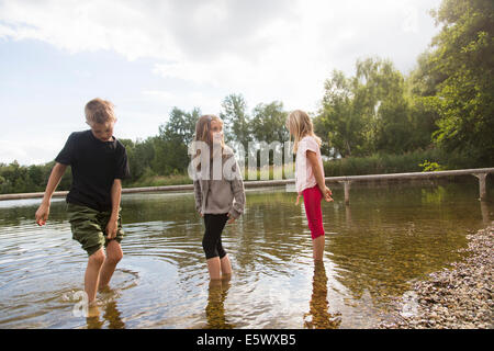 Bruder und zwei Schwestern im See paddeln Stockfoto