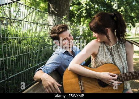 Junges Paar spielt akustische Gitarre im park Stockfoto