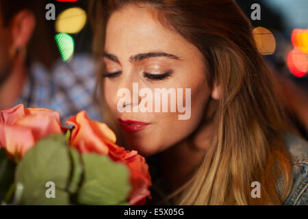 Junge Frau mit Freund duftende Rosen im Stadt-Taxi in der Nacht Stockfoto