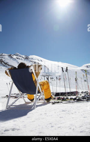 Rückansicht des Mitte erwachsenen männlichen Skifahrer sitzen auf Liegestuhl, Österreich Stockfoto