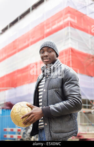 Porträt von lächelnden jungen Mann auf der Straße halten Fußball Stockfoto