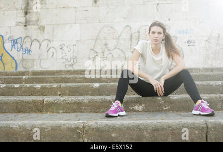 Sportliche junge Frau sitzen auf Stufen Stockfoto