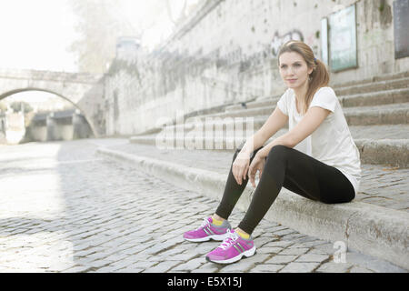 Sportliche junge Frau sitzen auf Stufen Stockfoto