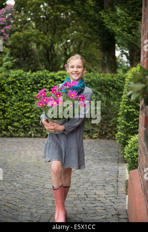 Porträt von Mädchen mit Blume Topfpflanze im Garten Stockfoto