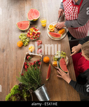 Erhöhte Ansicht des Mädchens und Großmutter am Küchentisch schneiden frisches Obst Stockfoto