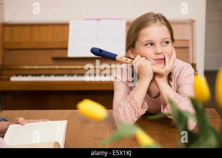 Gelangweilt abgelenkt Mädchen mit Recorder Instrument im Speisesaal Stockfoto