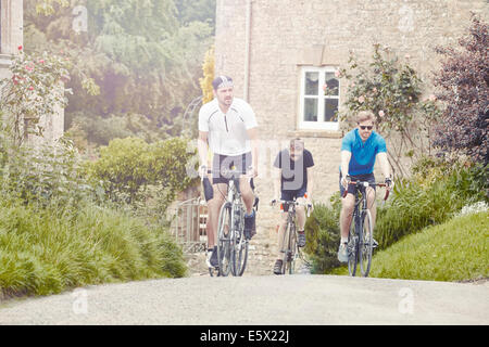 Radfahrer fahren durch Dorf, Cotswolds, UK Stockfoto