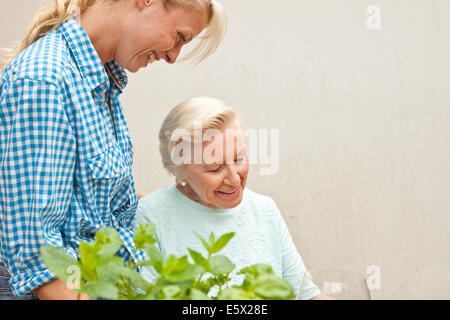 Ältere Frau und Enkelin im Chat am Gartentisch Stockfoto