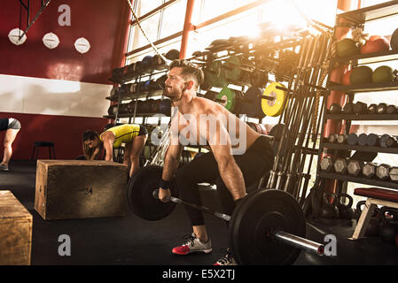 Bodybuilder, die Biegung um die Hantel heben Sie im Fitness-Studio Stockfoto