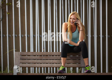 Frau im Chat auf Smartphone auf Parkbank Stockfoto