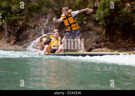 Brüder und Schwester spritzt aus Paddleboard auf hoher See Stockfoto