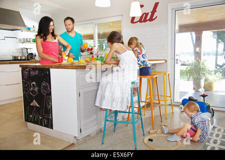Mitte Erwachsenen Eltern und seinen drei Kindern, die Zubereitung des Frühstücks in der Küche Stockfoto