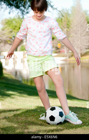 Zehn Jahre altes Mädchen spielen mit Fußball im park Stockfoto