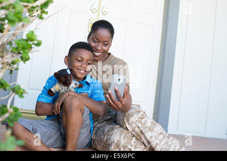 Soldatin unter Selfie mit Sohn an Haustür auf Heimkehr Stockfoto