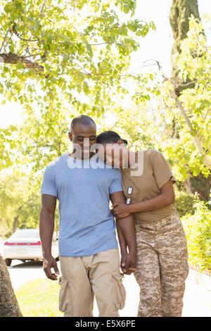 Soldatin Kopf auf Ehemänner Schulter ruht, beim Spaziergang auf Heimkehr Stockfoto
