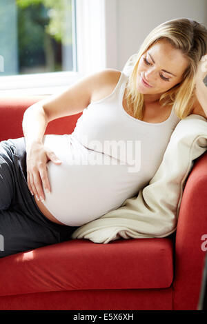 Schwangere Frau saß entspannend auf sofa Stockfoto