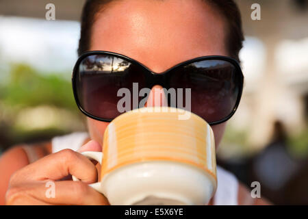 Nahaufnahme von Mitte Erwachsene Frau mit Sonnenbrille aus Kaffeetasse trinken Stockfoto