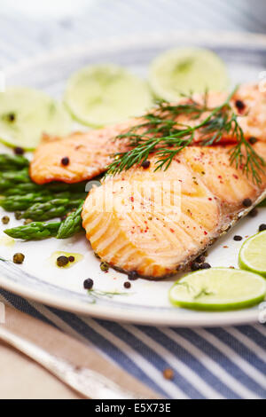 Lachsfilet mit Spargel in einer Schale mit einer blauen Umrandung und einem blauen Streifen Tischset Stockfoto