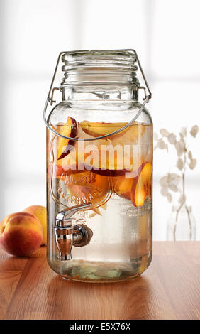 Glas mit Tap-Dispenser mit frischen Pfirsich Getränk Stockfoto