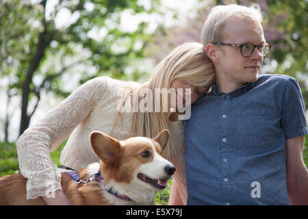 Junges Paar sitzt im Park mit Corgi Hund Stockfoto