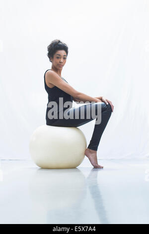 Junge Frau sitzt auf Fitness-ball Stockfoto