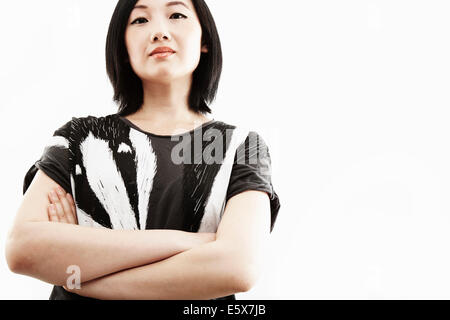 Studio-Porträt der jungen Frau mit verschränkten Armen Stockfoto