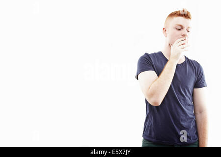 Studio-Porträt des jungen Mannes mit der Hand über den Mund Stockfoto