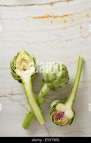 Drei frisch geschnittene Artischocken auf Marmor Oberfläche Stockfoto