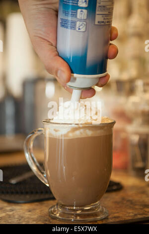 Nahaufnahme von Kellner squirting Schlagsahne auf Tasse heiße Schokolade Stockfoto