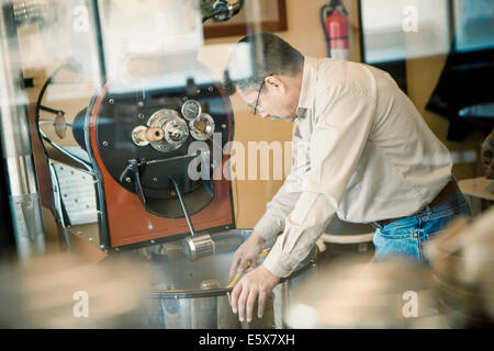 Reifer Mann mit Röstmaschine Kaffee im café Stockfoto