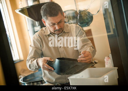 Reifer Mann mit Kaffeebohnen Kugel für Kaffeerösterei Maschine im café Stockfoto