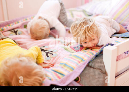 Drei junge Brüder kriechen verdeckt auf Bett Stockfoto