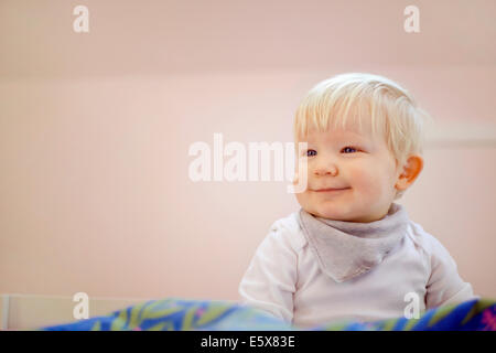 Porträt von niedlichen vierzehn Monate altes Baby Junge sitzt auf Bettdecke Stockfoto
