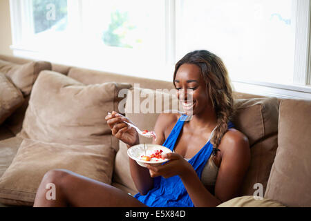 Junge Frau eine Ausbildung Pause, Essen Obst auf sofa Stockfoto