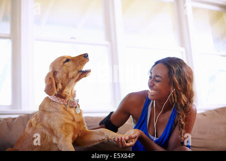 Junge Frau, die ein Training Pause, Petting Hund im Wohnzimmer Stockfoto